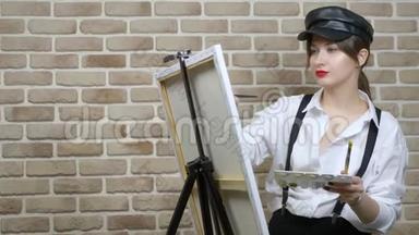 戴皮帽的女画家在画布上靠砖墙画一幅画